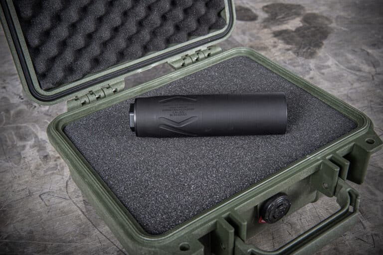 Black cylindrical device nestled in foam padding inside a rugged green protective case, open for transport.