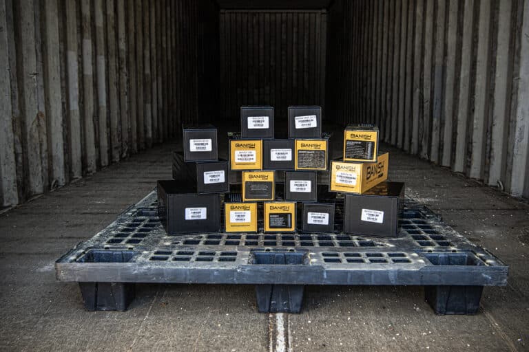 Stack of yellow-and-black Banish product boxes arranged on a pallet inside a dark trailer or cargo bay, ready for shipment.