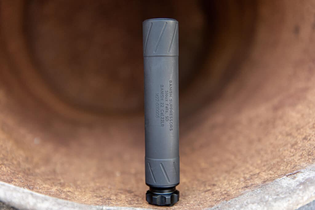 Close-up of a gray bicycle pump head attached to a valve on a brown surface.