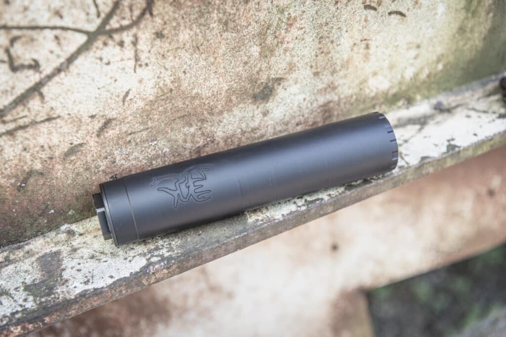 Close-up of a matte-black cylindrical vape pen resting on a mossy, weathered concrete surface.