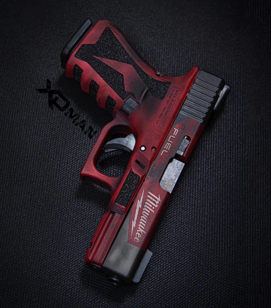 Red and black handgun-style airsoft pistol lying on dark fabric, with a textured grip and metallic slide.