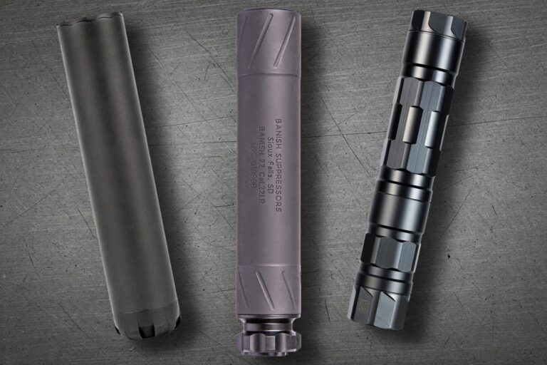 Three firearm suppressors laid out on a scratched metal surface: a long black canister on the left, a gray mid-length suppressor in the center with engraved branding, and a modular black-silver suppressor on the right (modular sections visible).