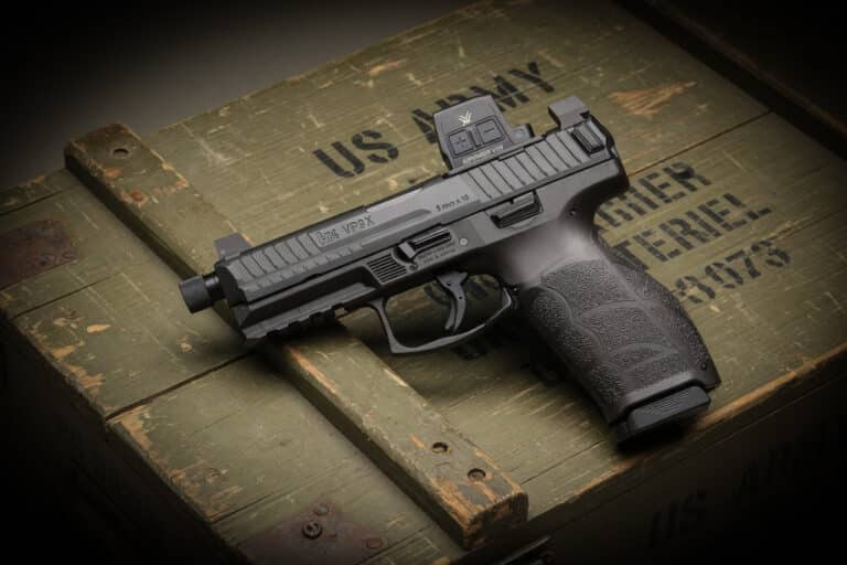 Semi-automatic pistol with textured grip and red-dot sight resting on a weathered green wooden crate marked 'US ARMY'.