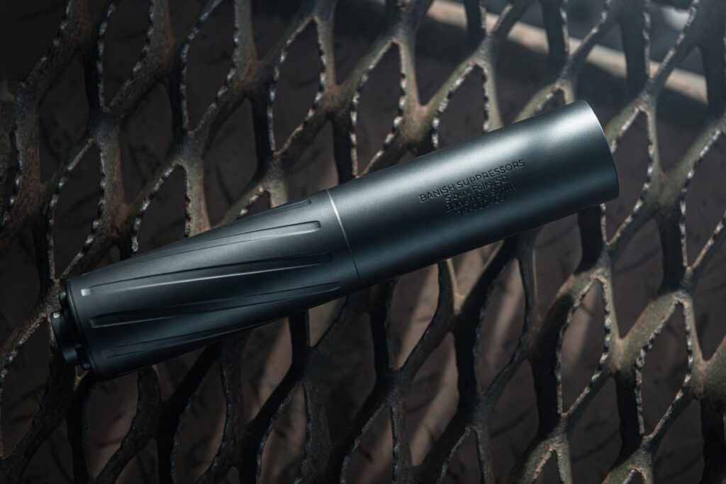 BANISH 9 suppressor resting diagonally on a rusty metal grate with'BANISH SUPPRESSORS' engraving visible