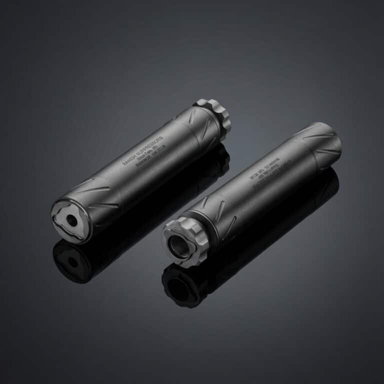 Pair of metallic firearm suppressors with knurled end caps on a reflective dark surface.