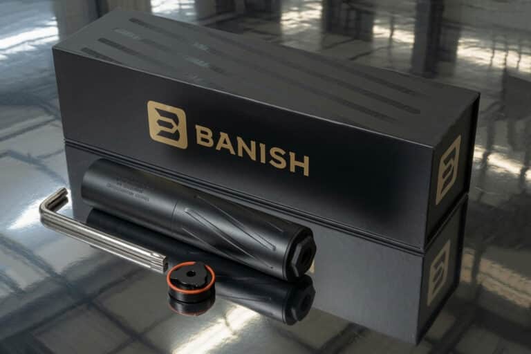 Banish tool kit with a black cylindrical handle, a metal rod, and an orange-ring cap on a reflective surface.