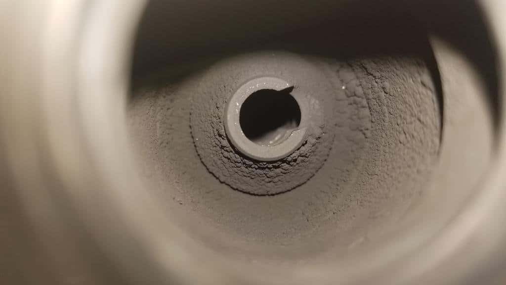 Close-up of a circular hole in rough, dusty material, seen from inside a tunnel.