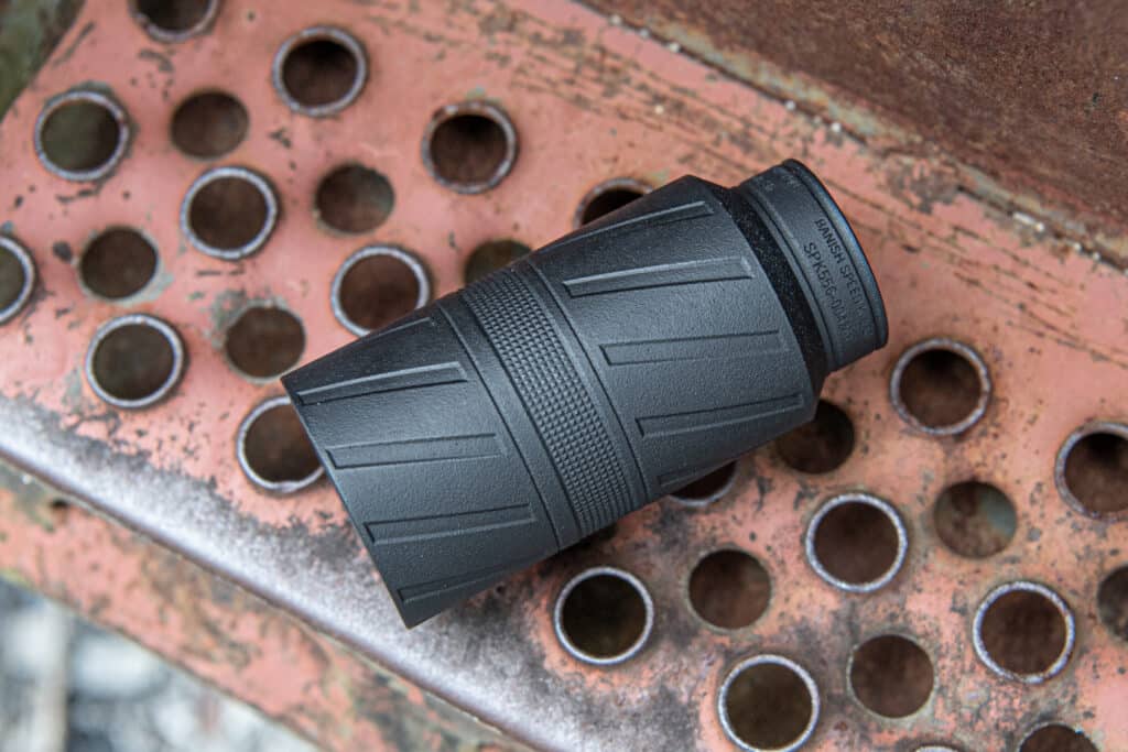 Close-up of a black plastic eyepiece resting on a rusted perforated metal surface.