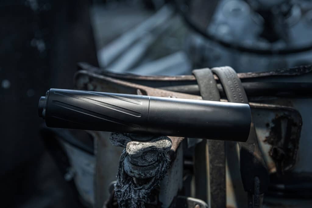 Black flashlight mounted horizontally on a weathered, rusty bicycle frame with a frayed strap nearby.